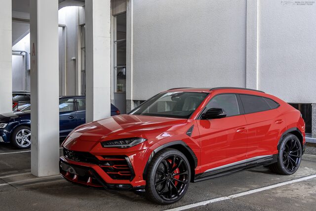 Lamborghini Urus vermelho estacionado sob colunas de concreto